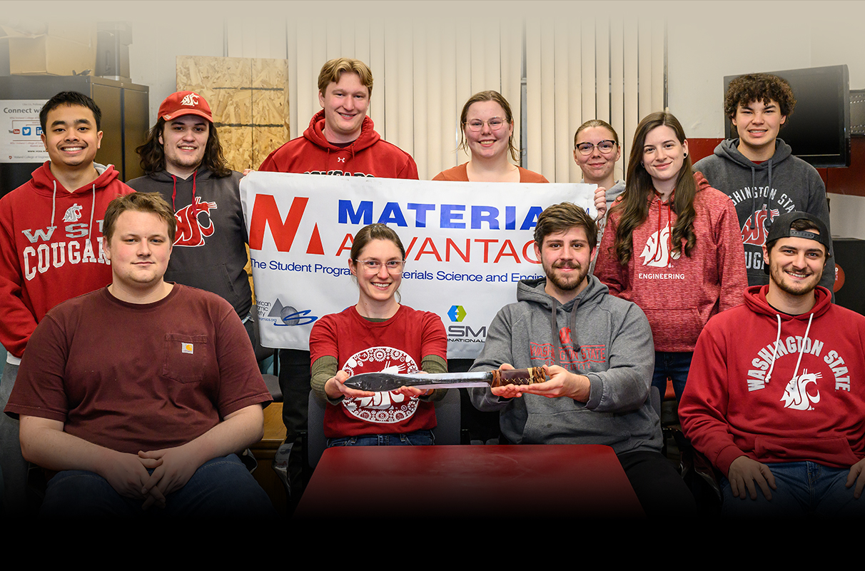Members of the WSU Material Advantage Club holding a club banner and showcasing a sword that they made.