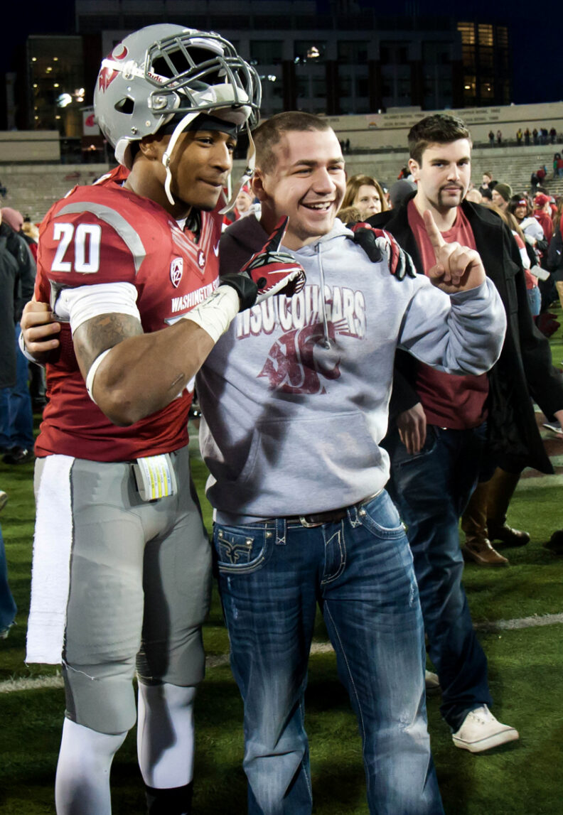 Deone Bucannon posing with a fan on the football field following a WSU win.