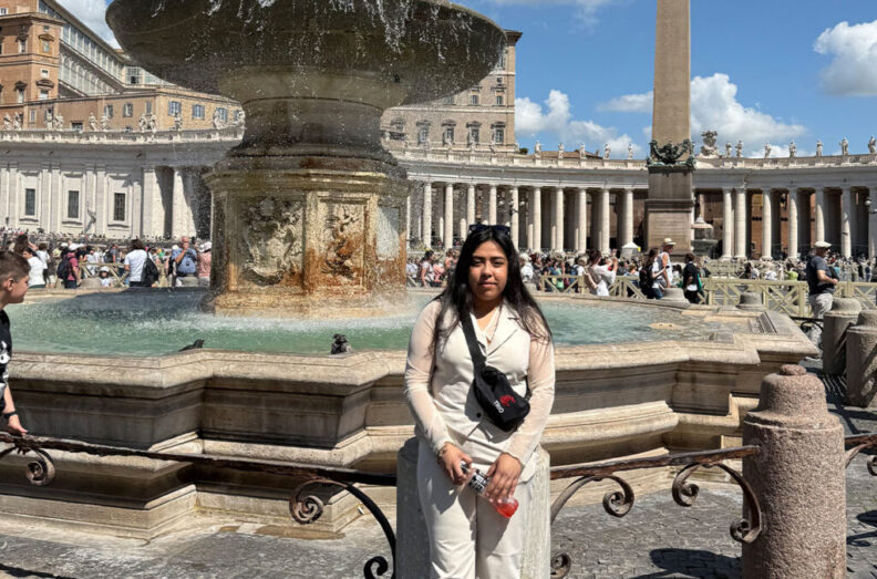 A woman stands in front of a fountain in Vatican City.