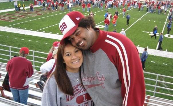 Visa and Serign Marong smiling for the camera in the stands of a football game.