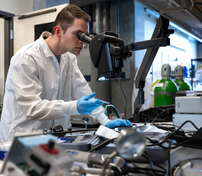 A student in a lab looking into a microscope.