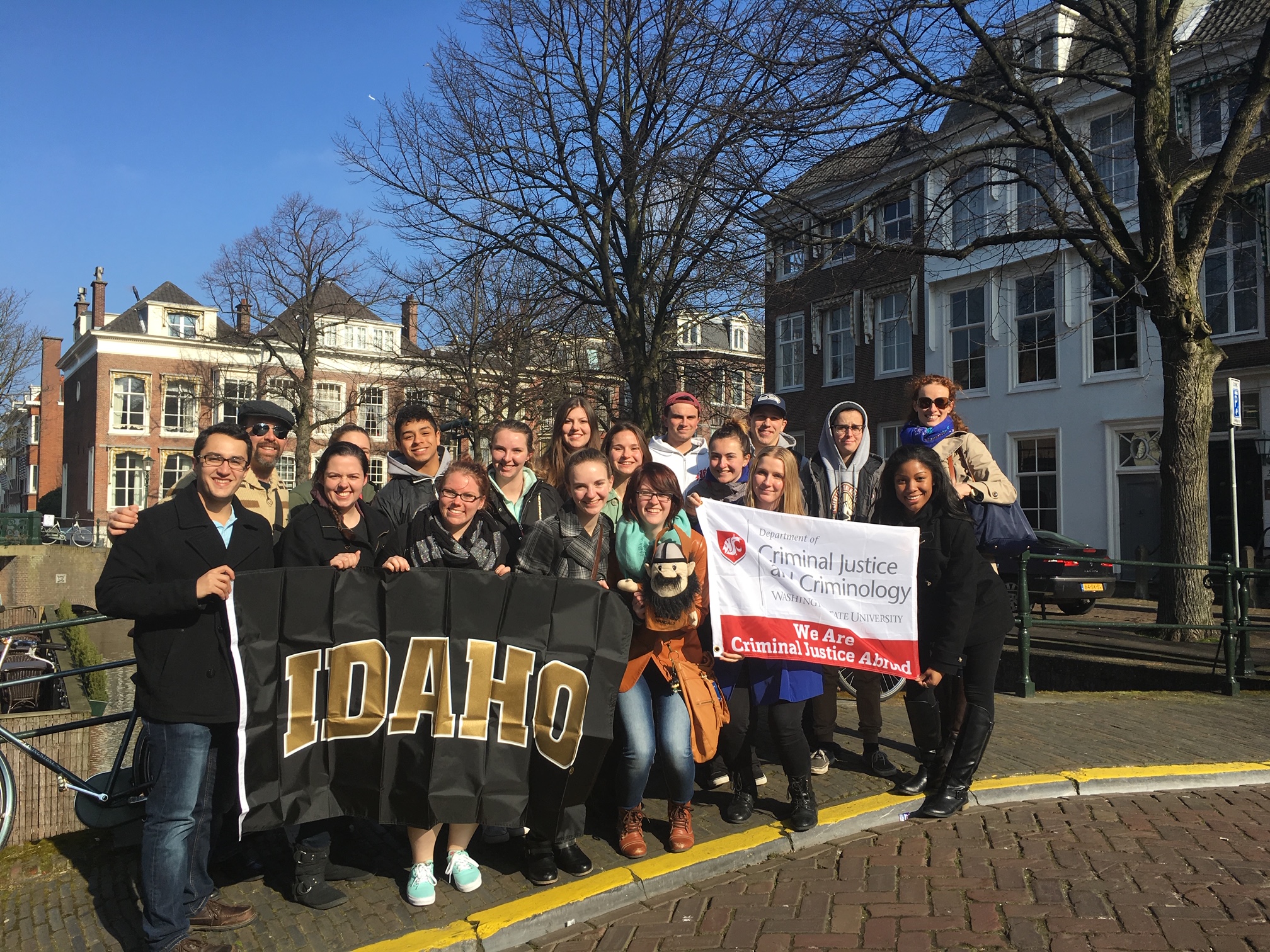 Study abroad students holding University of Idaho and WSU Criminal Justice and Criminology flags.