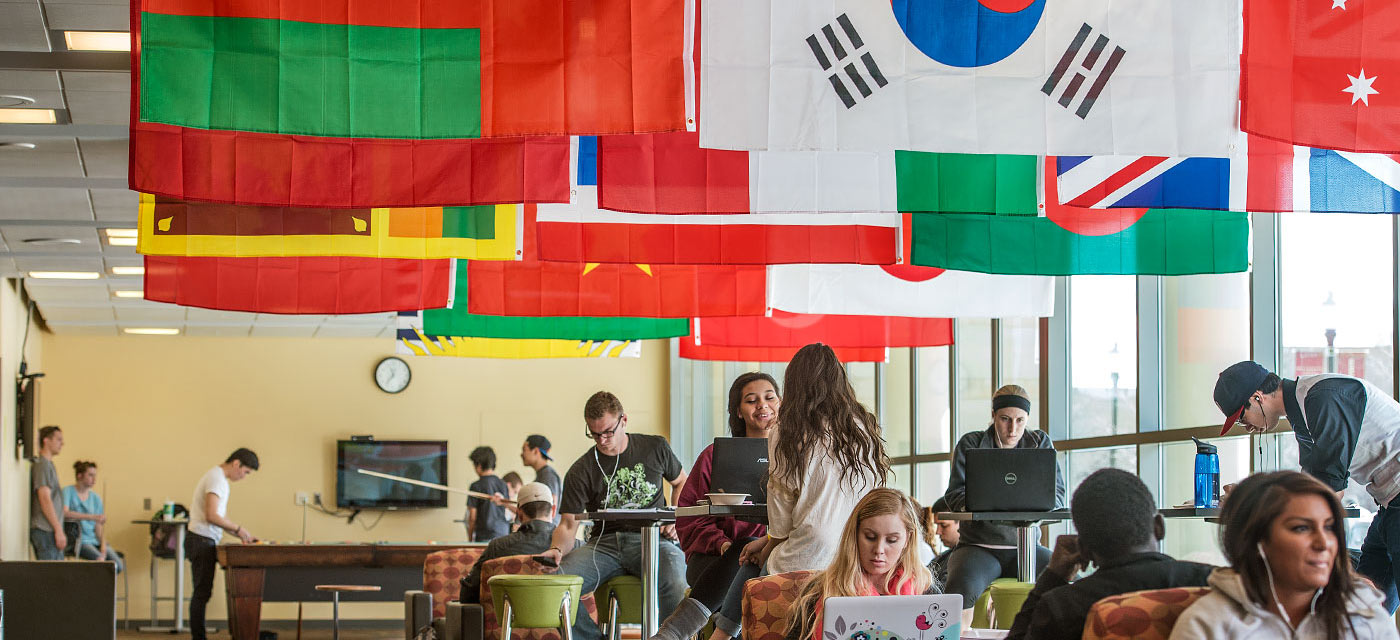 Students in the CUB with many international flags hanging from ceiling.