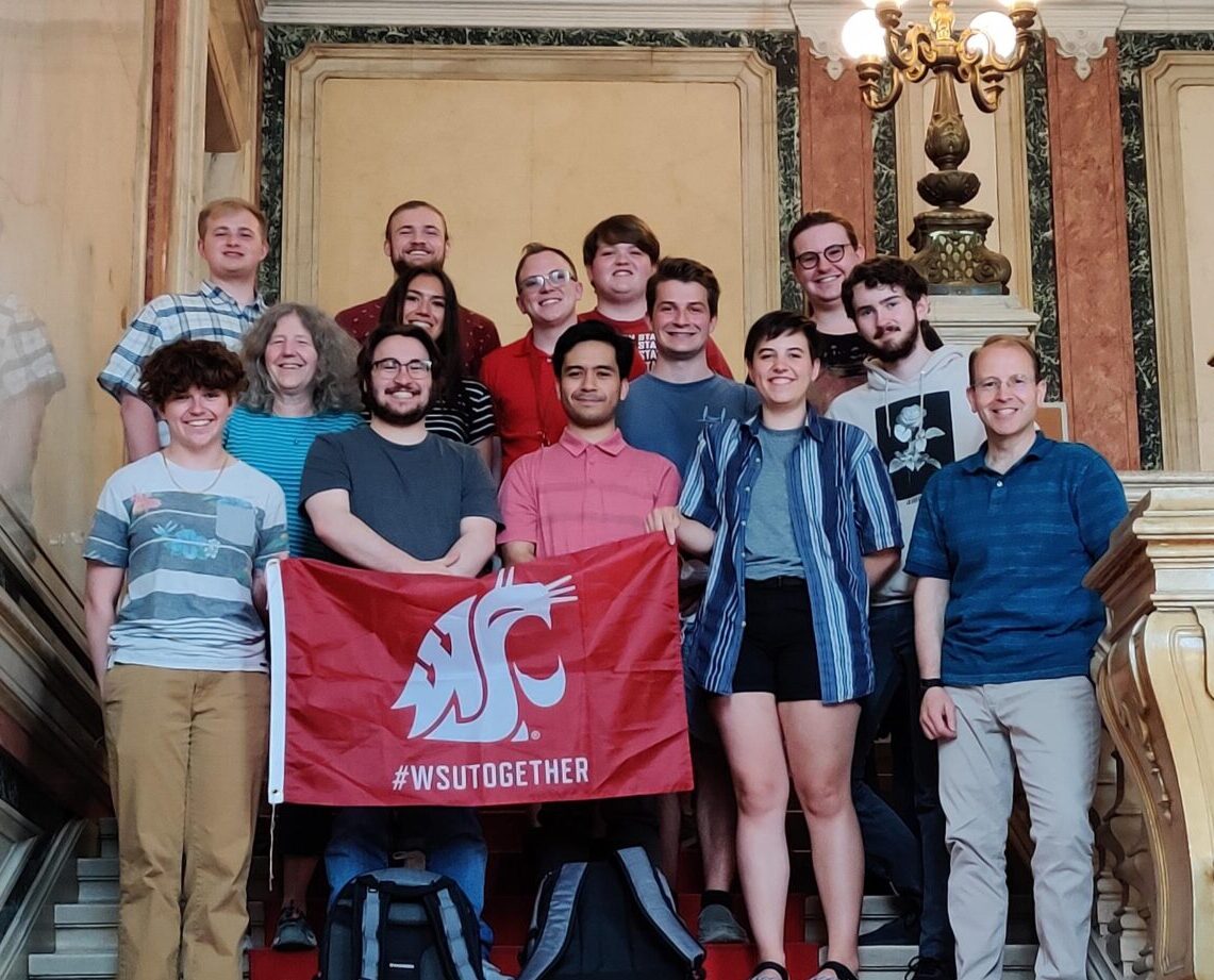 Study abroad students holding a cougar spirit flag.