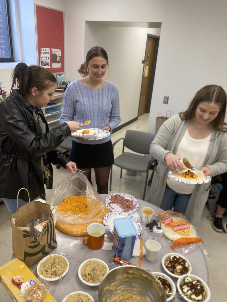 Three people getting food at table
