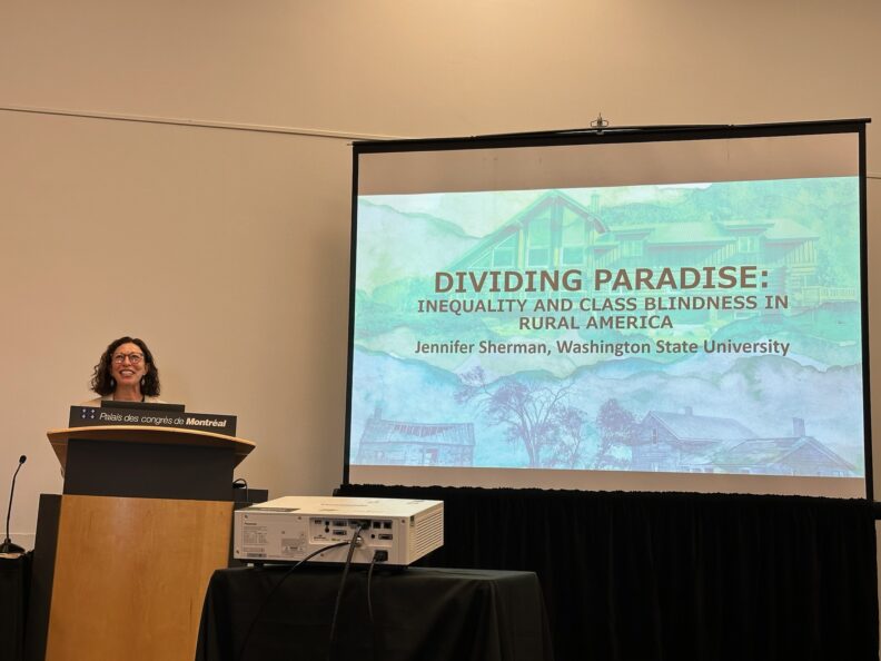 Sherman speaking at a podium giving a presentation.