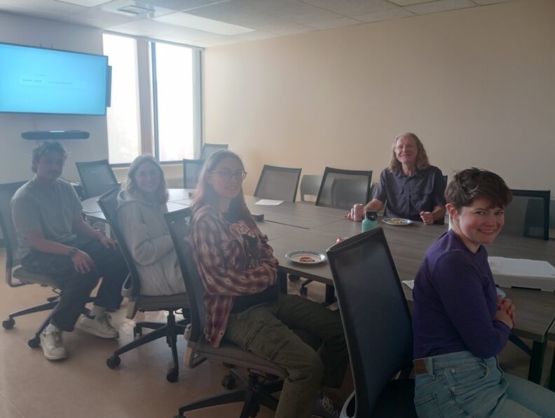 Richard sits at a table with several students.