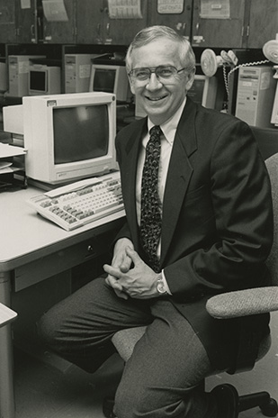 A black and white photo of Don sitting at a computer desk.