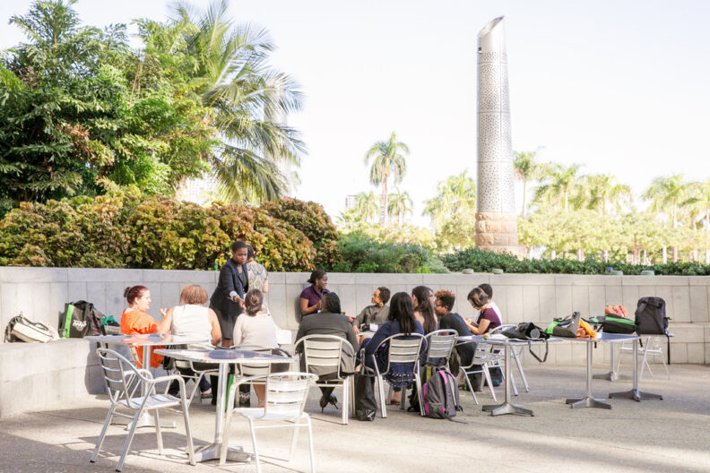 A group of about a dozen people meet on an outdoor patio.