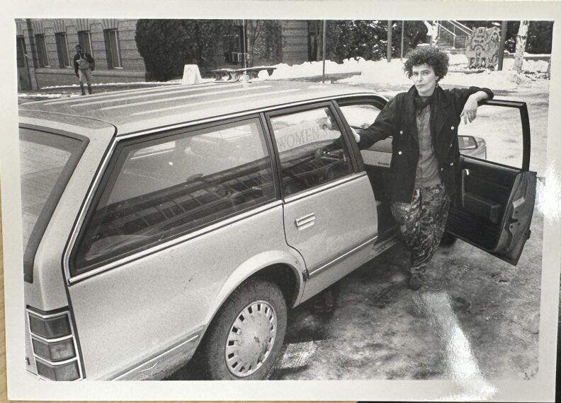 Photograph of Women's Transit Driver Sandi Carlton photographed with a car in 1992.