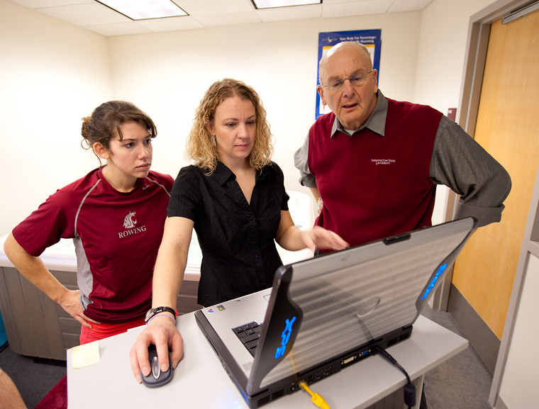 Students and faculty stand around a laptop.