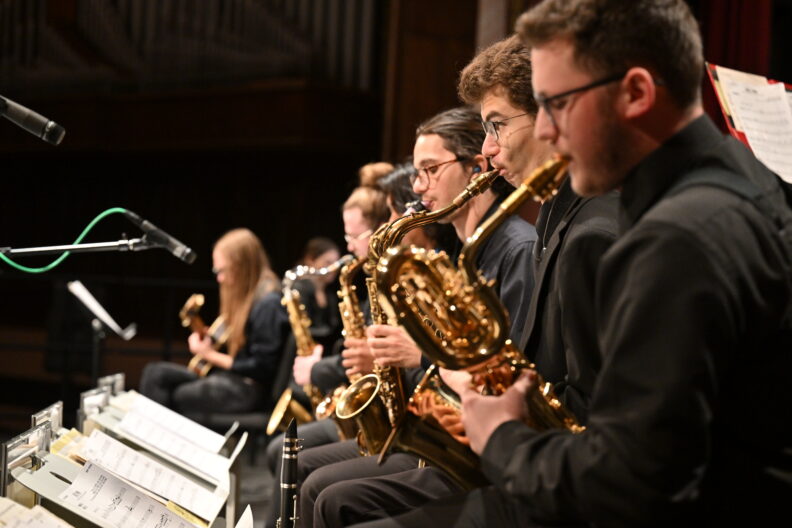 View of Jazz band saxophone section performing. (guitarist and pianist in background)