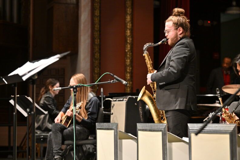 Tenor saxophone soloist performing with band. 