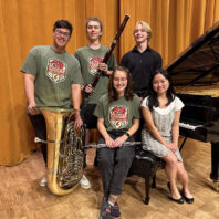 Five students on stage with instruments.