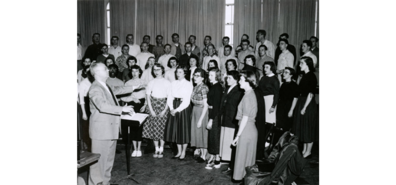 Choir director leading chorus members in song.