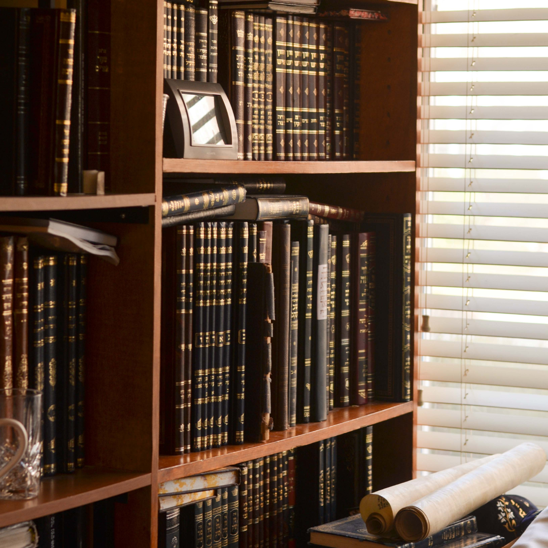 Image showing a bookcase beside scrolls of text on a desk. 