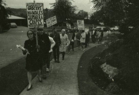 Picketers march down a sidewalk in this historic black and white photo.