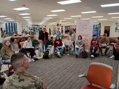 Students sitting in a circle at an exhibit.