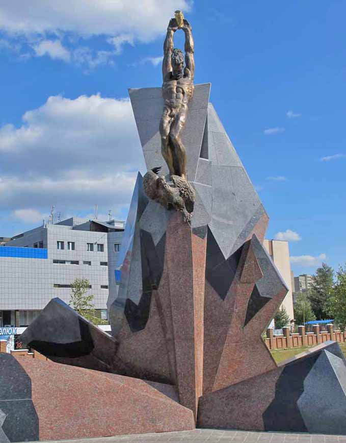 Sculpture of man holding what looks like a vase, high in the air and looking down at a bird that is falling. All pieces supported by a base that looks like a geometric explosion. 
