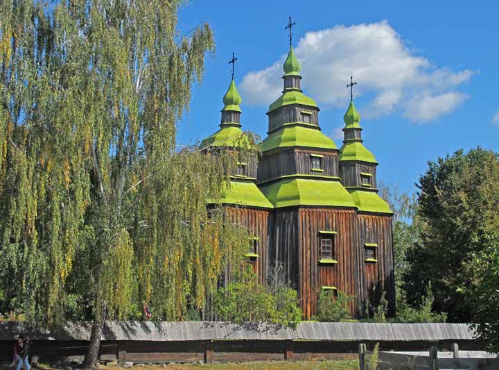 Church from the side with three spires and lime green roofs. 