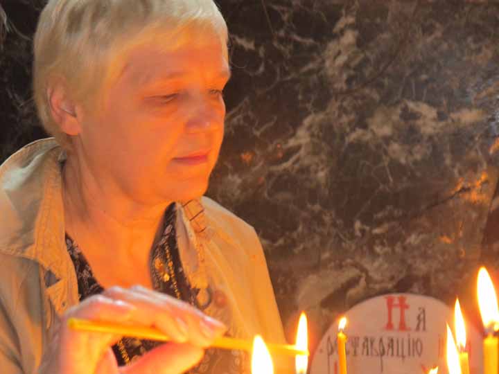 Lyubov reading in front of candles inside of the church. 