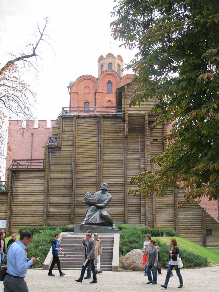 The Great Gate of Kiev with a statue of a person and a tall ornate building in the background. 