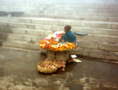 Varanasi (or "Benares," as the British called it), is the most sacred city of Hinduism. The goal of many is not only to bathe here in the holy Ganges, but to die in the central part of the city (known as Kashi) and be cremated on the ghats (water steps) and have their ashes thrown in the river. Because a major confrontation was expected at noon on this Friday between Muslims and Hindus worshipping at a contested site, we took a very early morning tour of the mist-shrouded city which was almost depopulated: fearful pilgrims were staying away to avoid the anticipated trouble. Flowers and clay pots for collecting sacred Ganges water for sale on the ghats (steps) by the river. Shot on a foggy morning in winter.
