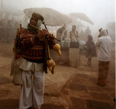 This vendor of musical instruments demonstrates his wares on a cold, foggy winter morning, at the top of the bathing ghats of Varanasi.
