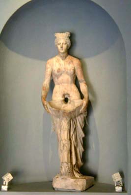Sculpture of person holding large shell in front of her - hole in sculpture that was used as a fountain is apparent.