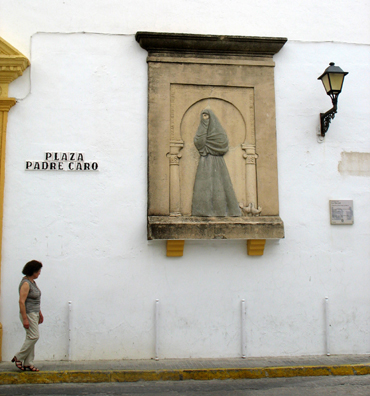 VEJER DE LA FRONTERA: Vejer was noted for centuries for its enveloping female garb, which left only one eye uncovered. The woman walking by this plaque memorializing the tradition illustrates typical modern dress.