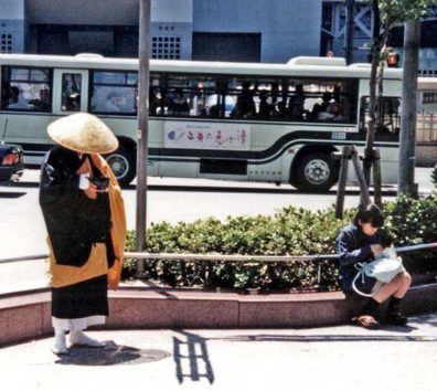 KYOTO: Buddhist monks are supposed to make their entire income from begging, but their begging style is very passive. The hat tilted down to cover the monk's face as he chants on this street corner prevents him from appealing for donations with his eyes. He remains entirely passive, relying on the good will and piety of passersby. May 13, 1998.