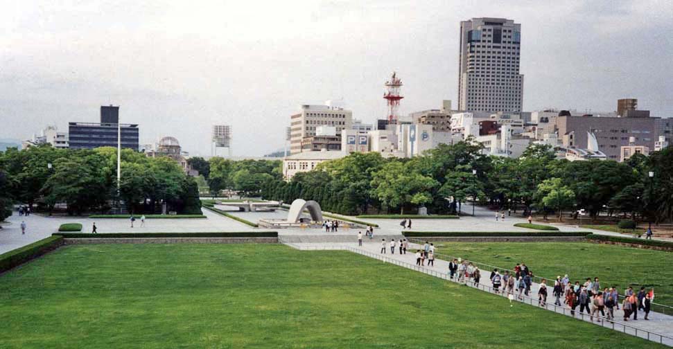 HIROSHIMA: View of the grounds of the Hiroshima Peace Park, site of the world's first atomic bombing (August 6, 1945). Brick crumbled, people evaporated and were burned, and the wood and paper houses were incinerated. Resistance was strong for many years to creating the park, but it is now a center for world peace activities. From the balcony of the museum, facing toward the memorial arch. Rear center is the "peace dome"--the concrete and steel exhibition hall that was directly under ground zero. Just to its left is a huge baseball stadium. In the background, modern Hiroshima. May 17, 1998