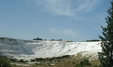 PAMUKKALE: Our next stop was a natural wonder, cliffs and pools of Pamukkale, coated in white calcium by mineral springs that flow over them. Posters for Turkey make this look like a vast area, but it's really fairly small, as this distant shot showing about a goodly portion of the site makes clear. Access to the site is limited to those willing to walk barefoot over the often painfully rough calicified surface. A long line of Europeans in bikinis wincing their way along the rocks is reminiscent of Medieval penitents inching on their knees along the streets of Campostella to the cathedral.