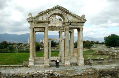 AFRODISIAS: The ancient city of Aphrodisias (Afrodisias), with a great temple dedicated to Aphrodite, goddess of love, is not often visited by tour groups. The best way for us to get there was to arrange for a taxi to take us from Pamukkale for the two-hour drive south, wait for us while we toured the site, and then take us on to Denizili to catch a bus. Fortunately, Turkish taxis are very cheap by American standards. Here we are standing in front of the imposing Tetrapylon, the ornamental gateway that greeted visitors headed for the Temple of Aphrodite, whose columns are visible in the background. Most of the monuments at Afrodisias date to the 2nd century CD and later.