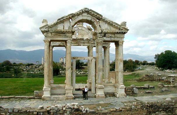 AFRODISIAS: The ancient city of Aphrodisias (Afrodisias), with a great temple dedicated to Aphrodite, goddess of love, is not often visited by tour groups. The best way for us to get there was to arrange for a taxi to take us from Pamukkale for the two-hour drive south, wait for us while we toured the site, and then take us on to Denizili to catch a bus. Fortunately, Turkish taxis are very cheap by American standards. Here we are standing in front of the imposing Tetrapylon, the ornamental gateway that greeted visitors headed for the Temple of Aphrodite, whose columns are visible in the background. Most of the monuments at Afrodisias date to the 2nd century CD and later.
