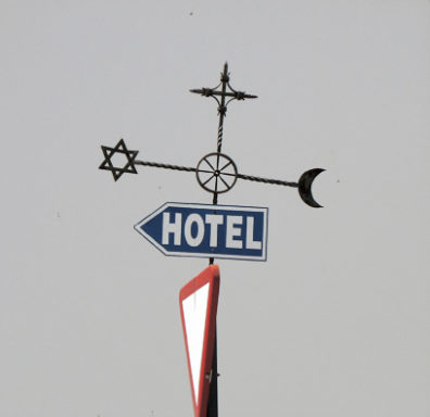 RONDA: This sign incorporates the Jewish star, the Christian cross, and the Muslim crescent in a gesture toward the mixed heritage of the area. We were uncertain whether to read the central wheel as Buddhist, since that religion has no roots here.