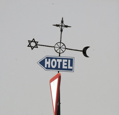 RONDA: This sign incorporates the Jewish star, the Christian cross, and the Muslim crescent in a gesture toward the mixed heritage of the area. We were uncertain whether to read the central wheel as Buddhist, since that religion has no roots here.