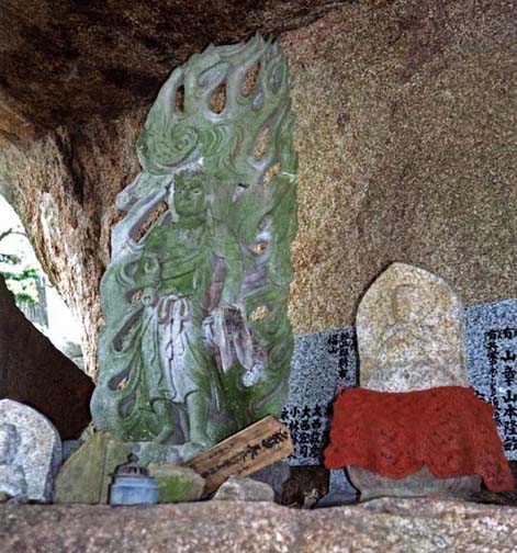 MIYAJIMA: The top of Mt. Misen is littered with huge, remarkably shaped stones, some of which shelter images like this one. Note the crocheted bib on the right-hand image of Jizo, Buddhist saint and protector of children. It is traditional for parents seeking help for an ailing child or hoping to improve its lot after death to dress a Jizo statue in a red bib. May 18, 1998
