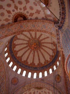 BLUE MASQUE: The interior of the great dome. The vertical wires support the lamps. The space is luminous, open. Despite its imposing size, the interior of the Blue Mosque gives a great impression of clarity. The rich ornamentation doesn't encrust it like some 17th-century European churches, but embellishes its grand, noble lines.
