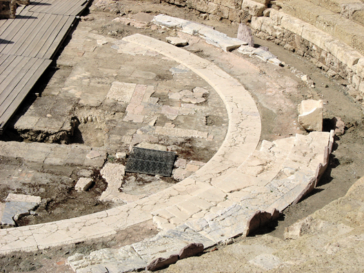 MALAGE: Closer view of the ancient stage area. The strips to the left make up a modern metal stage on which performances are held. Málaga had been settled in this area by Phoencians some time in the 7th century; but the Roman theater was built in the early years of the reign of Augustus.