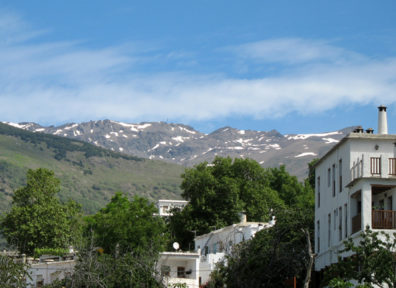 LAS ALPUJARRAS: A more detailed view of the Sierra Nevadas. At the right of the photo, note the characteristic chimney pot which is a sort of trademark for the town. The region below the mountains is known as “Las Alpujarras,” a name whose origin is in some dispute.