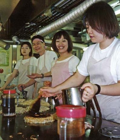 HIROSHIMA: Misleadingly called "Japanese pizza," okonomiaki is a popular food in parts of Japan, especially in Hiroshima. The customer chooses from a wide variety of ingredients, including various vegetables and--in this case--fried noodles (a specialty of Hiroshima), and the whole is formed into a cake, fused together with egg, and fried on a grill in front of you, brushed with a "syrup" that gives okonomiaki it's distinctive taste. These are tiny, informal joints specializing in fast food. The result is delicious, but nothing like pizza. May 18, 1998