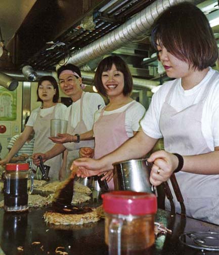 HIROSHIMA: Misleadingly called "Japanese pizza," okonomiaki is a popular food in parts of Japan, especially in Hiroshima. The customer chooses from a wide variety of ingredients, including various vegetables and--in this case--fried noodles (a specialty of Hiroshima), and the whole is formed into a cake, fused together with egg, and fried on a grill in front of you, brushed with a "syrup" that gives okonomiaki it's distinctive taste. These are tiny, informal joints specializing in fast food. The result is delicious, but nothing like pizza. May 18, 1998