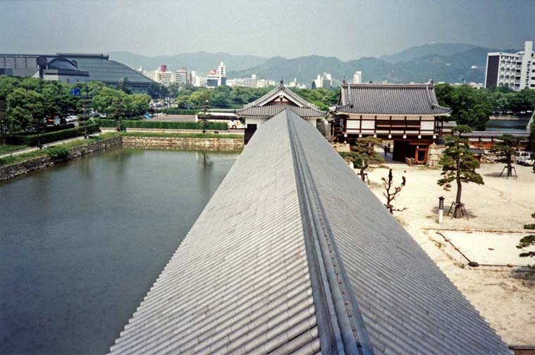 Moat running along the wall of the reconstructed Hiroshima Castle grounds, photographed from on top of the wall, which now encloses a museum. In the distance on the left, the Hiroshima baseball stadium. May 19, 1998