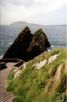 DINGLE PENINSULA: These striking rocks mark the boat landing where people can set off for the Blasket Islands (visible in the distance), now abandoned, but once occupied by a hardy group of folks who produced a striking number of fine books memorialized in the spectacular Blasket Centre in Dún Chaoin, where we viewed a film of the history of the islands. Because most of the audience was made up of an Irish-speaking local high school group, we had to wear headphones to hear an English translation. Much of the Dingle Peninsula is Gaeltacht, an area where Gaelic is promoted and sustained. We heard it used on the streets in Dingle, even by young people, quite casually.
