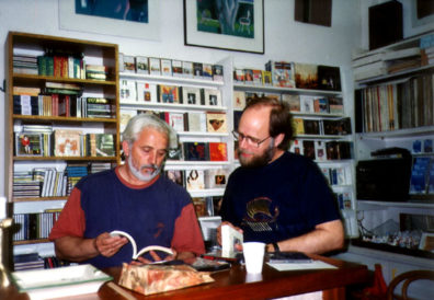 OLYMPIA: Finally we arrived in the thriving modern tourist town of Olympia, which has as high a concentration of tacky souvenirs as the Plaka in Athens. However, we discovered a fine little record and book shop at the end of the street which displayed this sign in its window: Pour ceux qui cherchent la Grece sans cliché ["For those who seek Greece without cliches"]. The owner conversed at length with us about the recordings of Byzantine and Classical music we had seen in Athens and opened packages to let us hear samples and study the documentation. He also offered us wine (the gold merchants of Olympia usually offer ouzo to promising customers). We rewarded him by spending heavily. It was a nice experience. Paul is wearing the new t-shirt Paula has just bought him, embroidered with the image from the 50-drachma coin: an ancient ship.