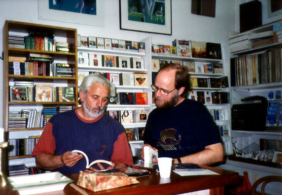 OLYMPIA: Finally we arrived in the thriving modern tourist town of Olympia, which has as high a concentration of tacky souvenirs as the Plaka in Athens. However, we discovered a fine little record and book shop at the end of the street which displayed this sign in its window: Pour ceux qui cherchent la Grece sans cliché ["For those who seek Greece without cliches"]. The owner conversed at length with us about the recordings of Byzantine and Classical music we had seen in Athens and opened packages to let us hear samples and study the documentation. He also offered us wine (the gold merchants of Olympia usually offer ouzo to promising customers). We rewarded him by spending heavily. It was a nice experience. Paul is wearing the new t-shirt Paula has just bought him, embroidered with the image from the 50-drachma coin: an ancient ship.