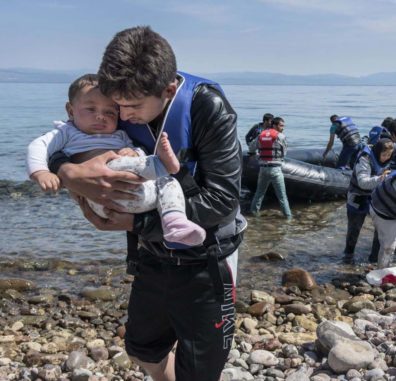 Refugee holding baby on shore leaving boat