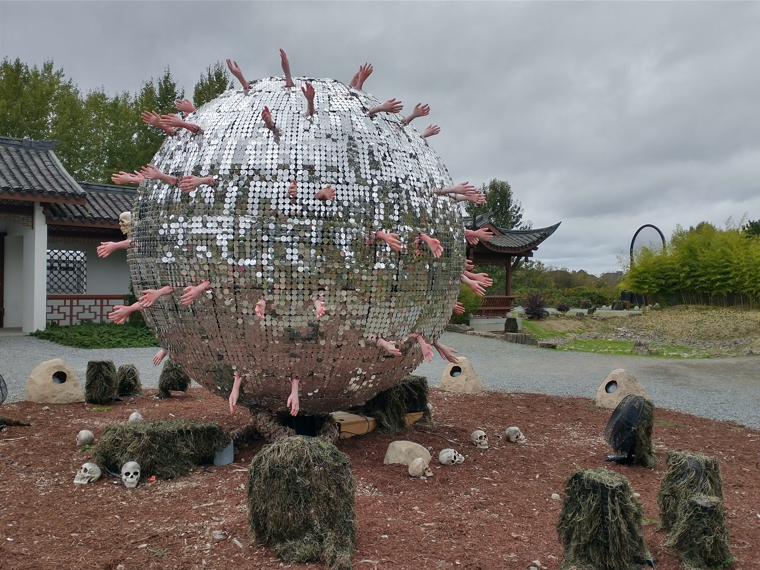 A sculpture of a disco ball with hands sticking out of it