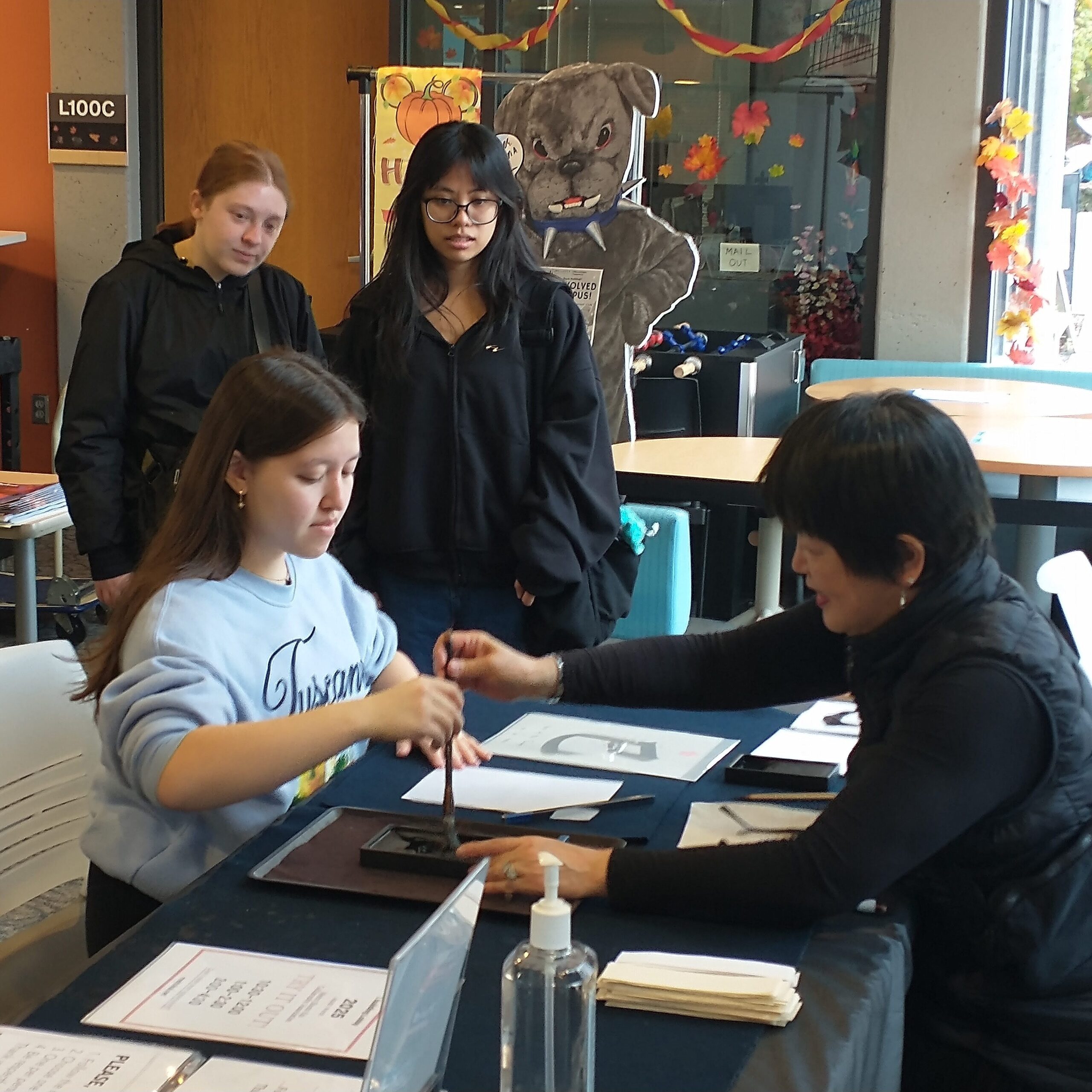 Students working with language mentors in a hands-on learning exercise to create calligraphy with ink and brush.